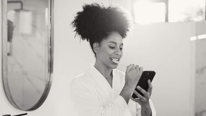 Woman brushing teeth while on social media