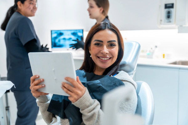Lady holding up an iPad at a dental office. ABOBA Digital Solutions can provide dental offices with devices and workstations as part of their add on services.
