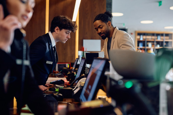 Hotel staff working on agency provided computers and attending to guest.